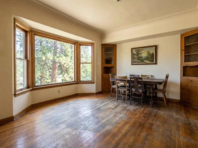 Dining room oak floor with a faded, grayed and worn area by the bay window before refinishing