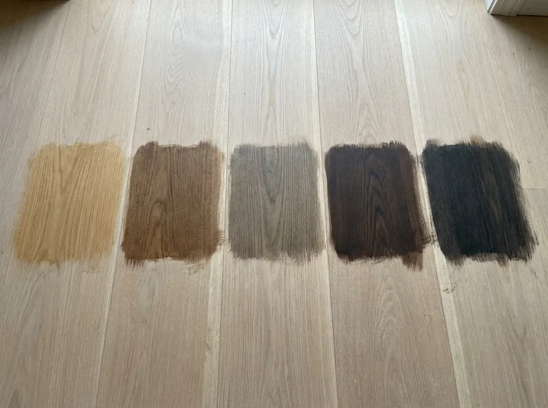 Five stain test patches from light honey to dark espresso on a freshly sanded white oak floor
